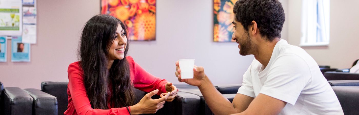 A male and female researcher in conversation in a break room