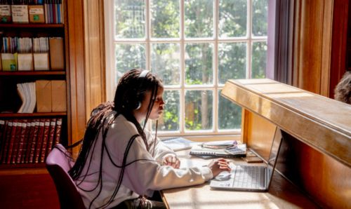 Student working in Main Library by a window